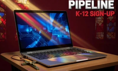 Chromebook with brass crucifix and stained glass light beam over Catholic school AI training scene.